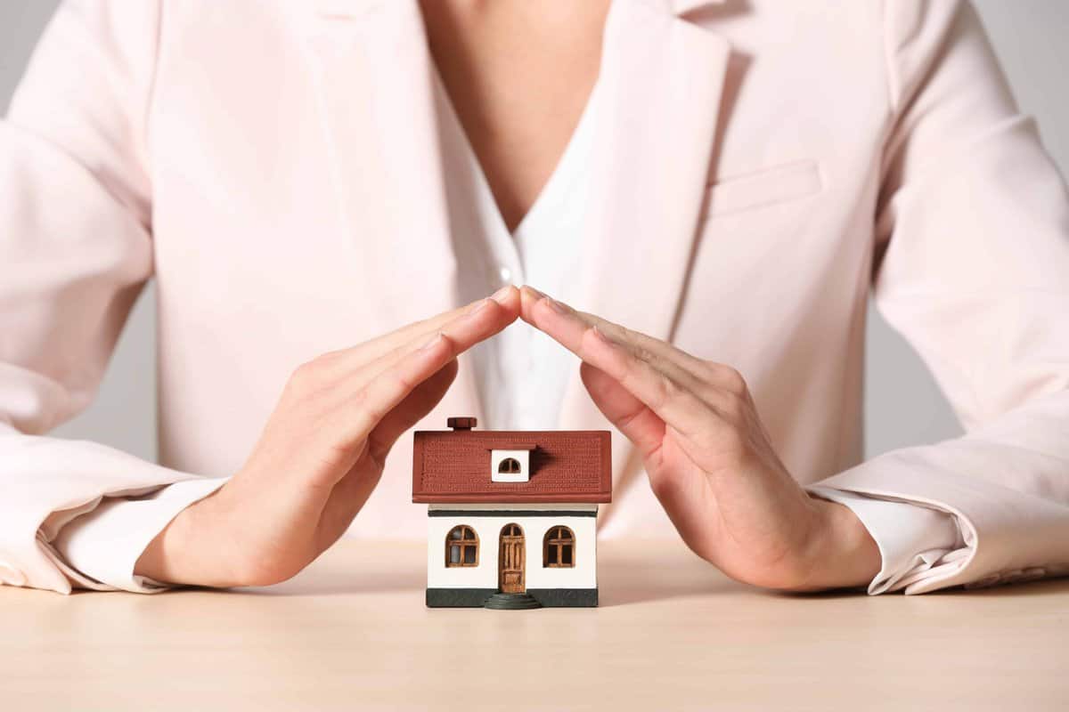 A woman contemplating available housing assistance options at a table with a small house in front of her.