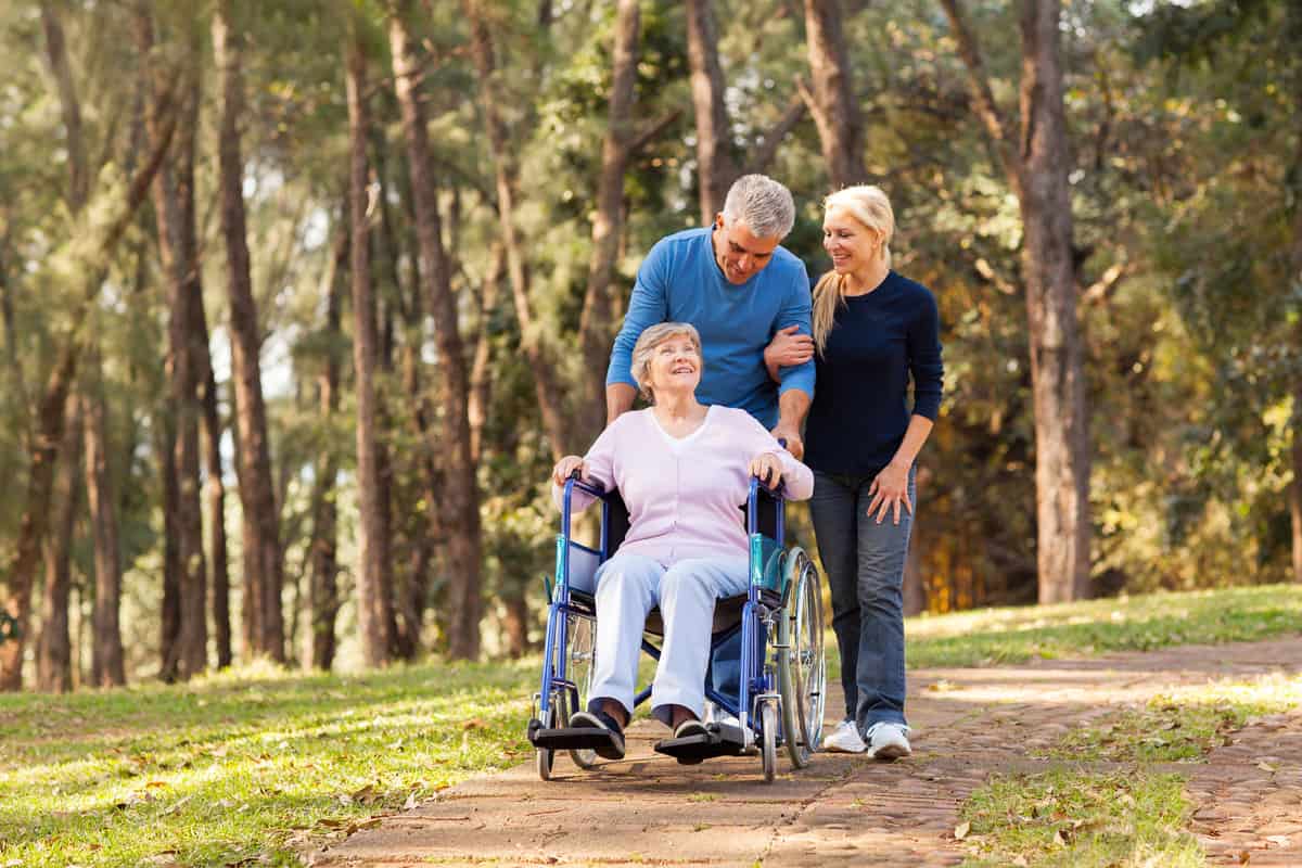 couple taking their disabled senior mother for a walk